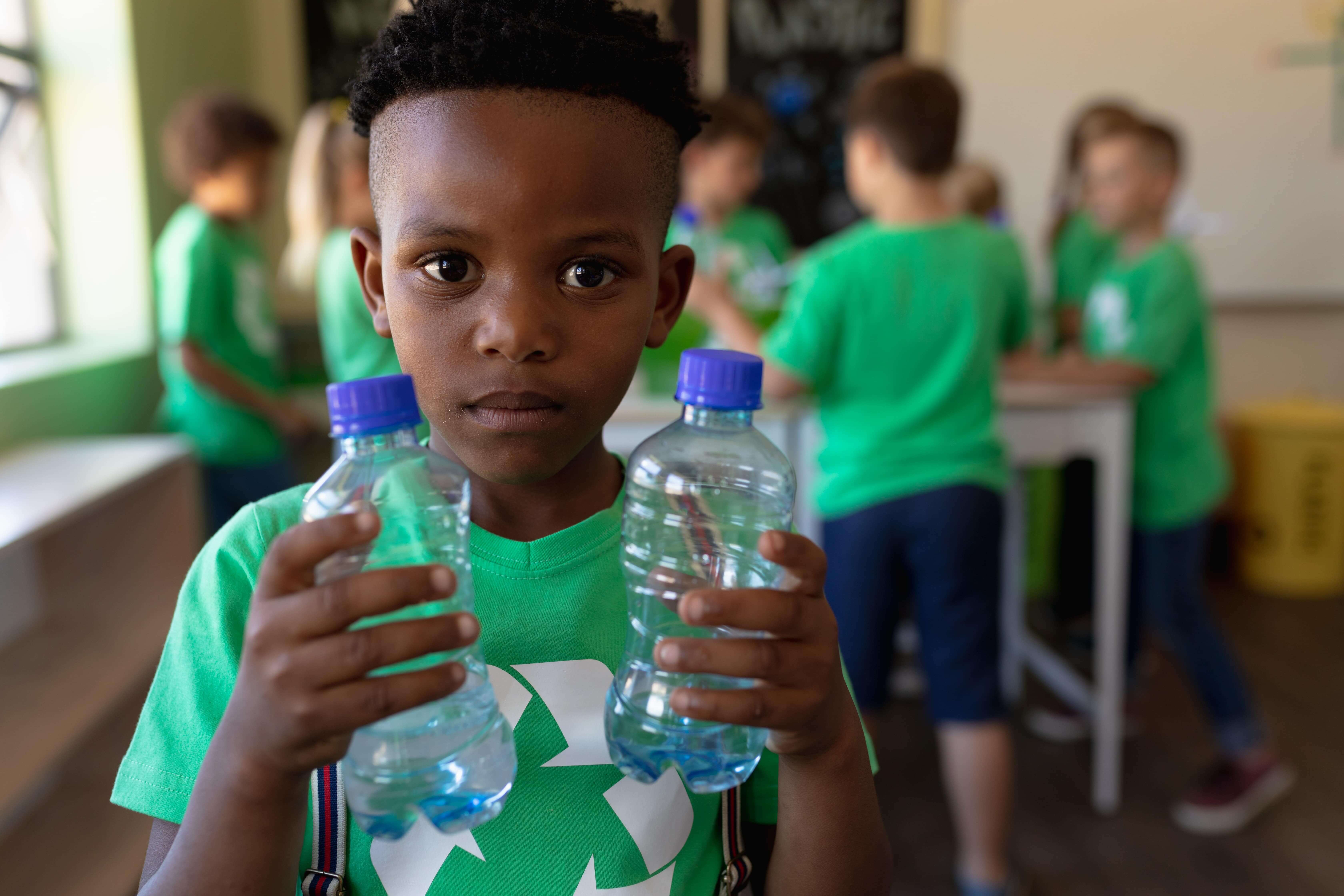 boy on green holding plastic bottles